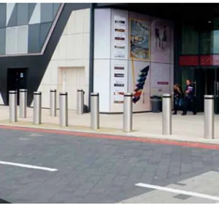 PAS-rated stainless steel security bollards installed outside a modern commercial building entrance, providing hostile vehicle mitigation and pedestrian safety – fpgulf.com.