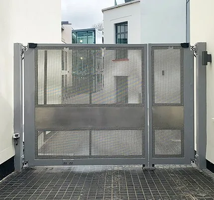 Industrial hinged swing security gate with mesh infill for secure perimeter vehicle access control.