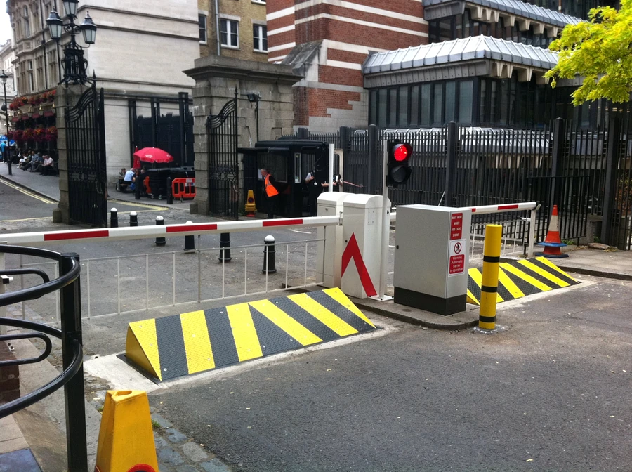 Automatic vehicle access barriers with traffic lights and safety bollards securing a controlled entrance to a commercial facility.