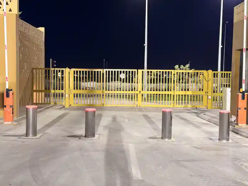 Side view of a yellow Terra Bi-fold Gate installed at a private villa, designed for high-security access control with IWA 14 and LPS 1175 certification under EN 12453 standards.