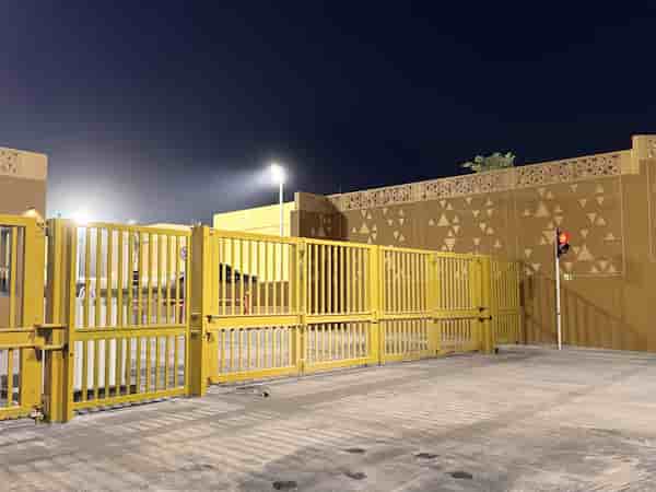 Front view of a certified IWA 14 and LPS 1175 Terra Bi-fold Gate installed at a high-security private villa, featuring integrated bollards and perimeter protection under night lighting.